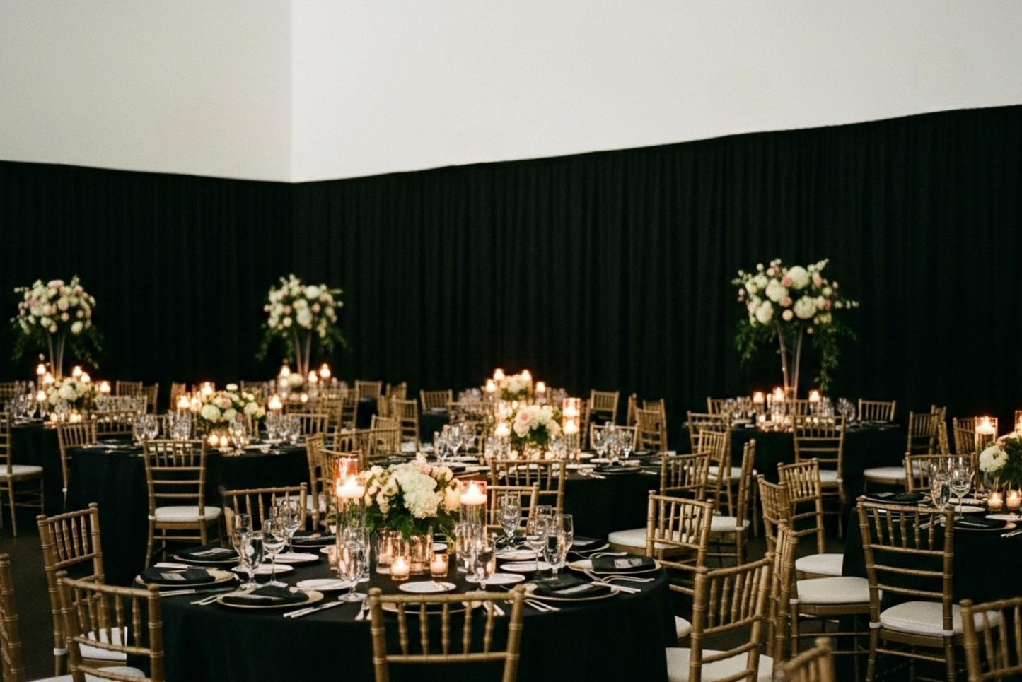 Black fabric background with gold wedding chairs and ivory cushions.