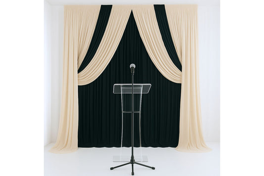 Black curtain with beige drapes behind a clear lectern and wireless microphone on stand