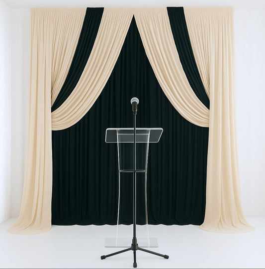 Pipe-and-drape backdrop with black and beige drapes behind a clear lectern podium, with a wireless microphone on a stand.