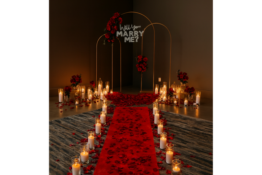 Romantic proposal setup with red carpet, candles, and 'Will You Marry Me?' sign.