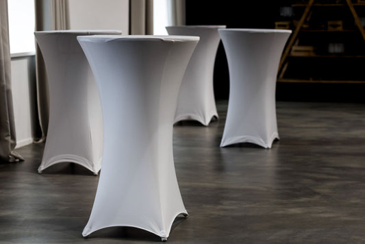 White cocktail tables with stretch covers on a wooden floor.
