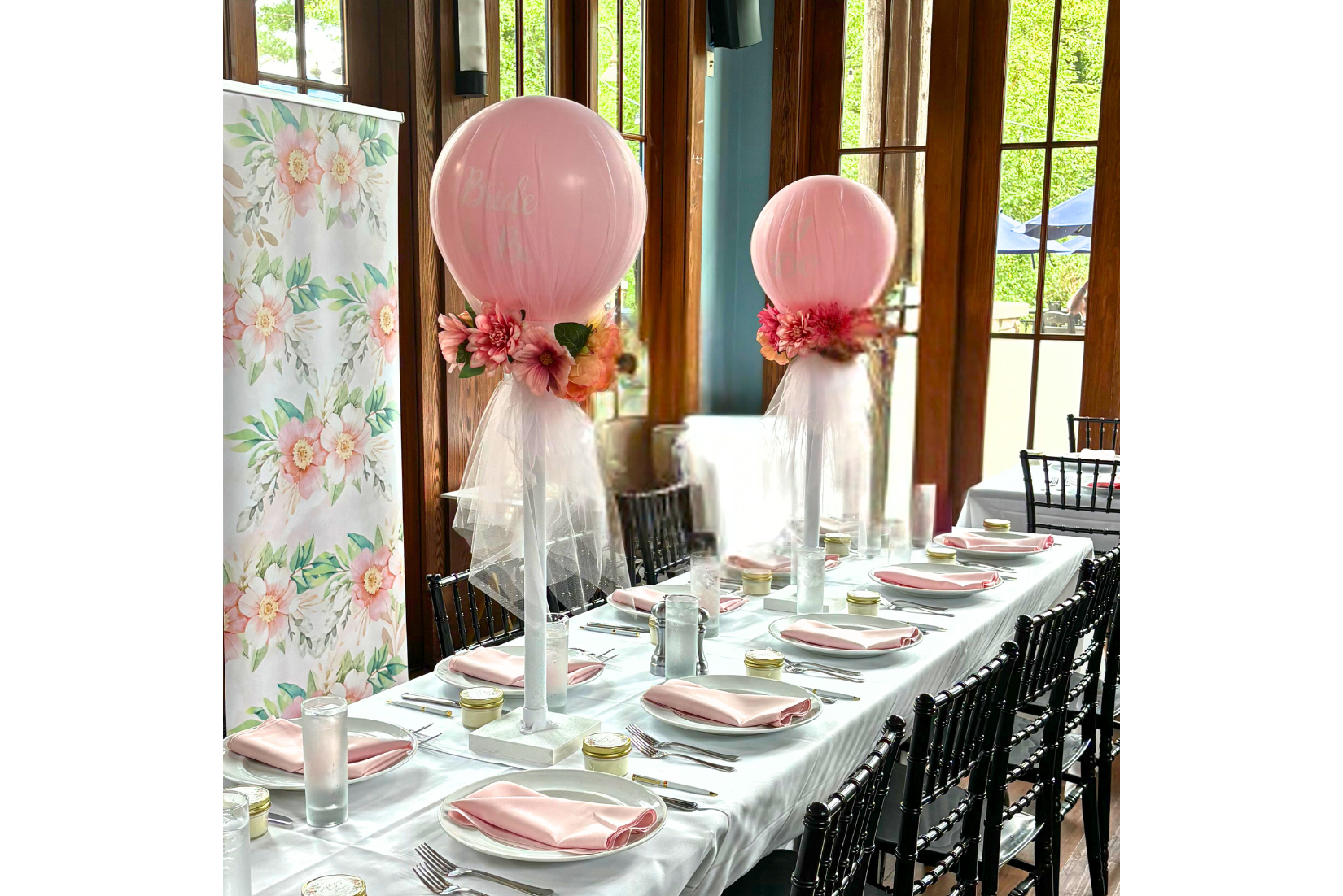 Balloon table centerpiece with custom text, tulle, and flowers with a printed floral photo backdrop
