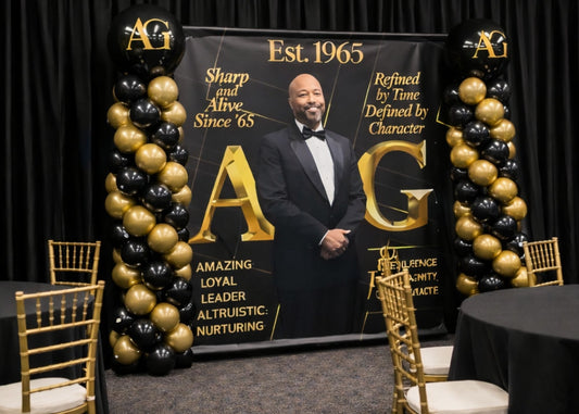 Black and gold step and repeat birthday banner featuring a man in a suit and text, surrounded by balloons and chairs.