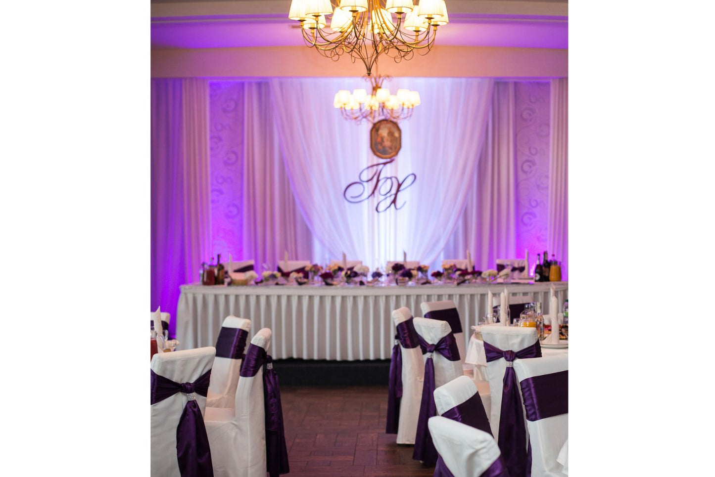 Purple uplighting to spotlight a monogram for wedding reception.