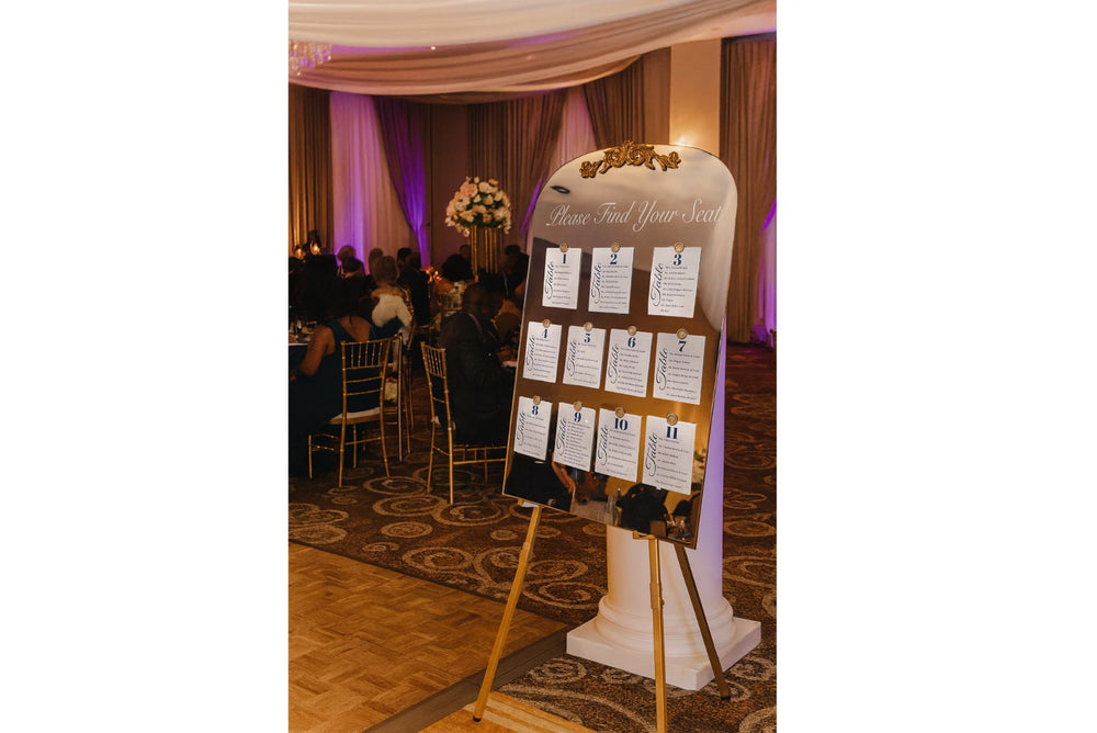 Easel gold color with custom welcome and seating chart on mirror.