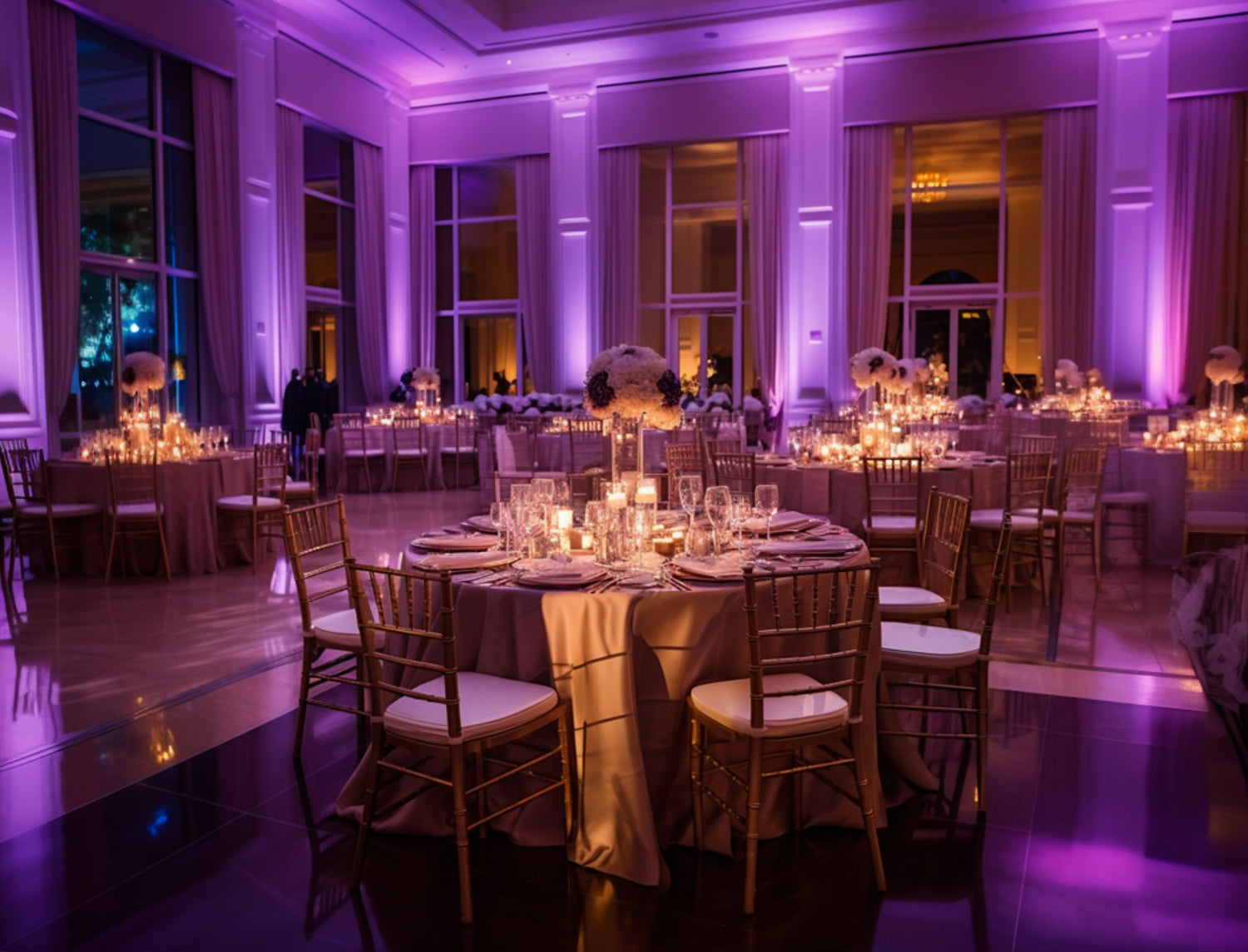 Magenta colored uplighting with chiavari chairs and floating candle table centerpieces.