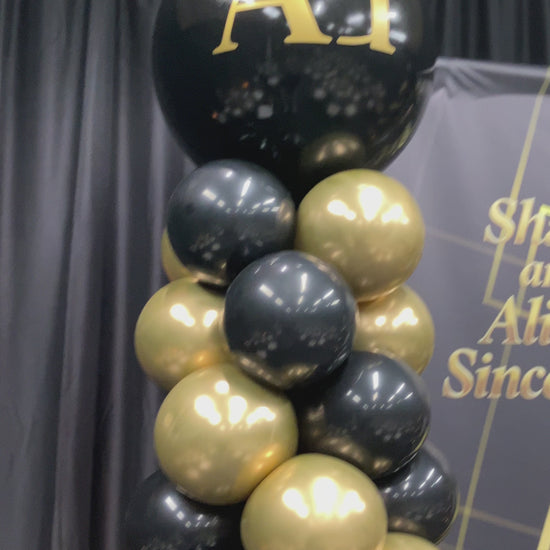Video of black and gold balloon column with monogram on large balloon topper.