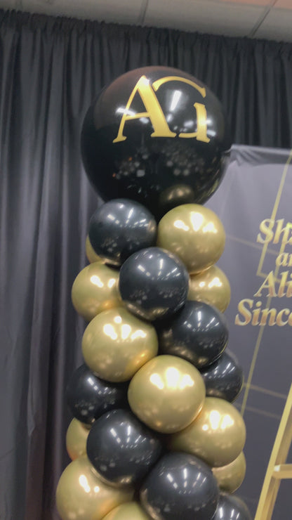 Video of black and gold balloon column with monogram on large balloon topper.