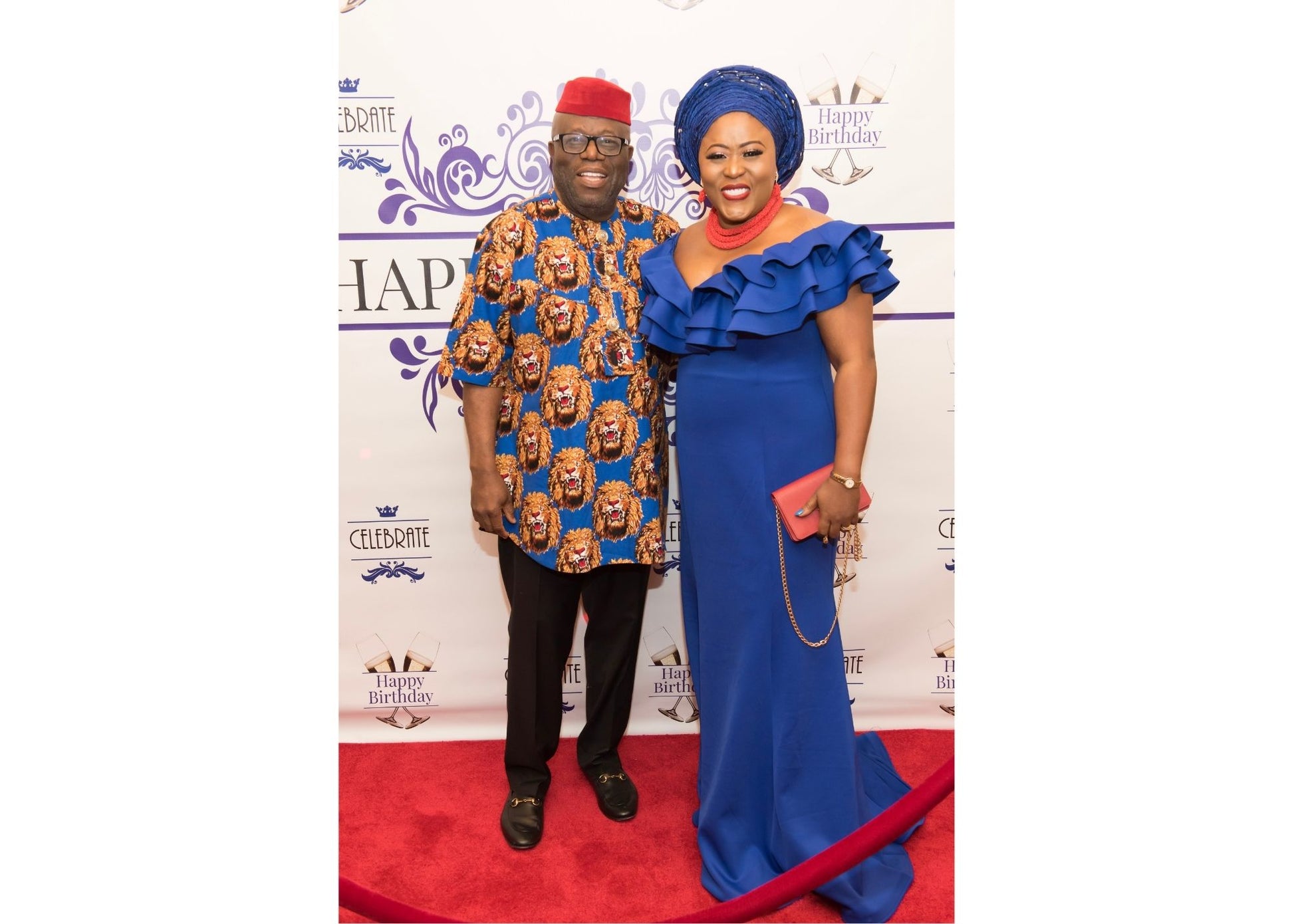 Two people posing on a red carpet event with a branded backdrop
