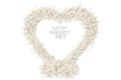 Heart-shaped arrangement of white flowers with small 'Will you marry me?' neon sign.